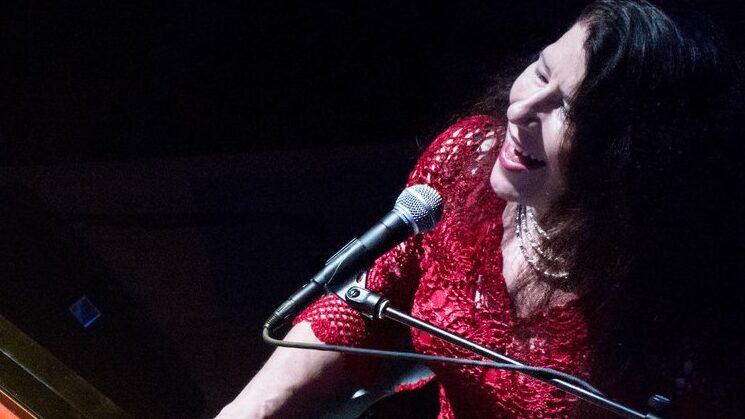 Wendy DeWitt at the piano with a microphone